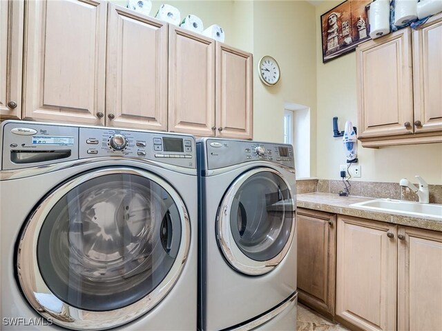 clothes washing area featuring cabinets, washer and dryer, and sink