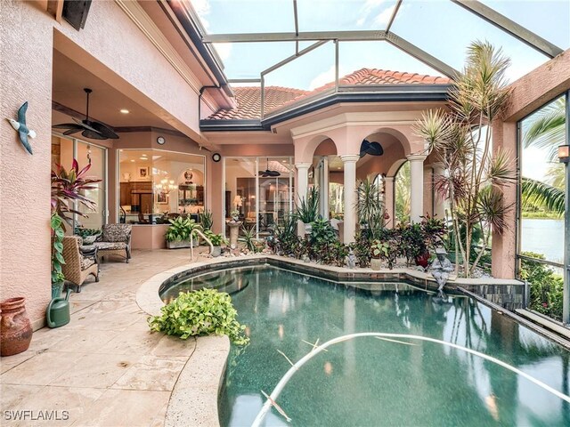 view of swimming pool with glass enclosure, ceiling fan, and a patio area