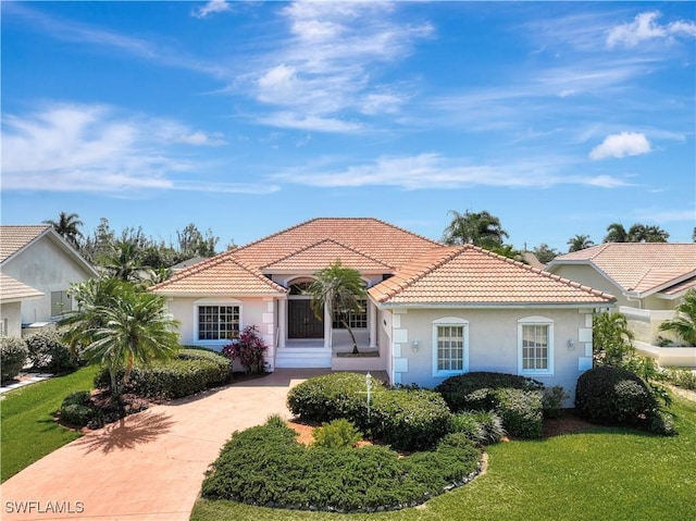 mediterranean / spanish-style house with a tiled roof, a front yard, and stucco siding