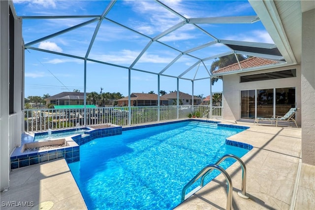 view of pool featuring a pool with connected hot tub, glass enclosure, and a patio