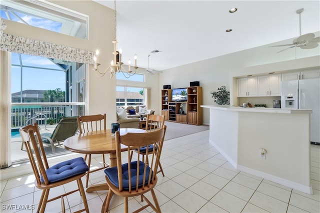 dining area with light tile patterned floors, baseboards, visible vents, and ceiling fan with notable chandelier