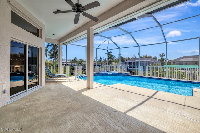 view of pool with a patio, glass enclosure, and ceiling fan