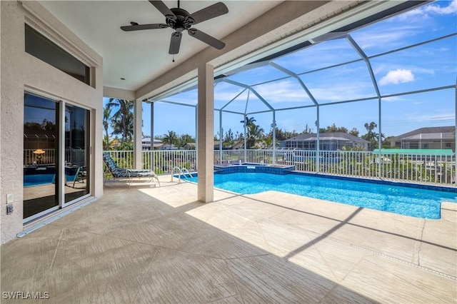 view of swimming pool with a patio, a pool with connected hot tub, a ceiling fan, fence, and a lanai