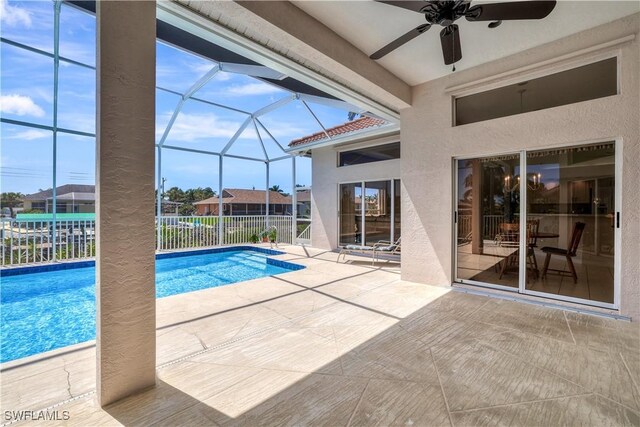 view of swimming pool featuring ceiling fan, a patio, and a lanai