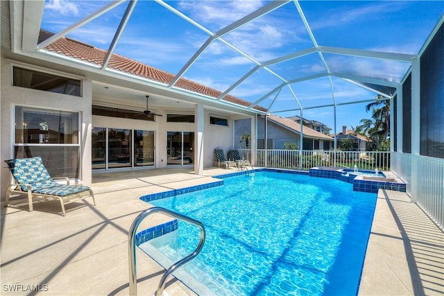 view of pool with a pool with connected hot tub, glass enclosure, a patio area, and a ceiling fan