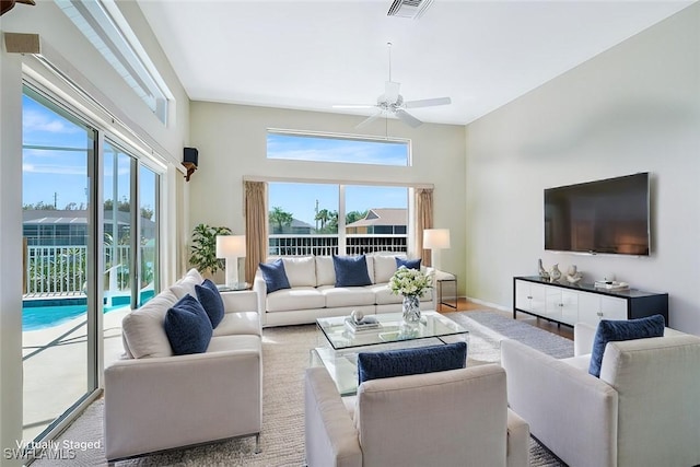 living area with baseboards, visible vents, ceiling fan, and a wealth of natural light