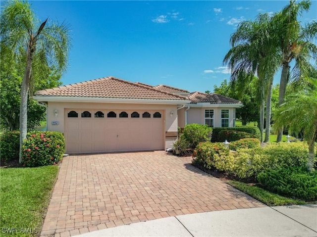 view of front of home featuring an attached garage, a tile roof, decorative driveway, and stucco siding