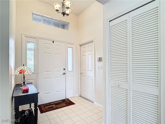 entryway featuring a chandelier, light tile patterned floors, and baseboards