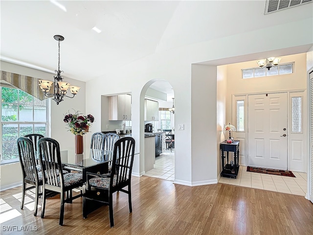 dining area with lofted ceiling, a notable chandelier, and light wood-type flooring