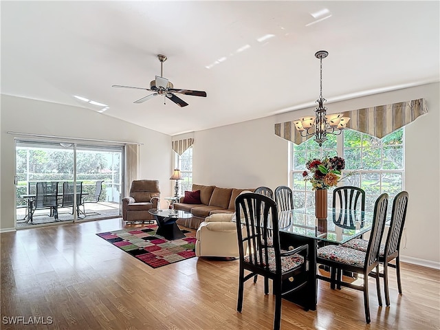 dining space featuring vaulted ceiling, ceiling fan with notable chandelier, and hardwood / wood-style flooring