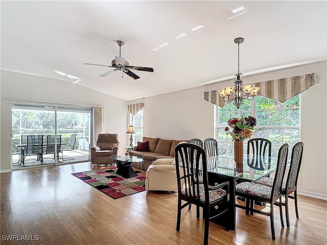 dining room featuring ceiling fan with notable chandelier, vaulted ceiling, baseboards, and wood finished floors