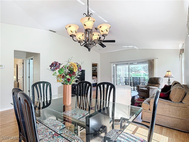 dining area with light wood-type flooring, ceiling fan with notable chandelier, and vaulted ceiling