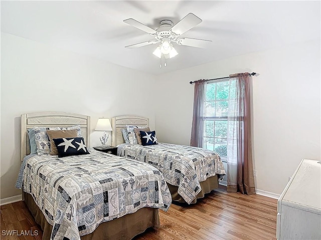 bedroom with ceiling fan, baseboards, and wood finished floors