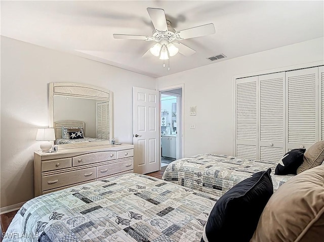 bedroom featuring dark wood-type flooring, a closet, visible vents, and a ceiling fan