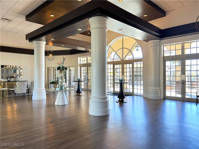 exercise room featuring a towering ceiling, french doors, hardwood / wood-style floors, and decorative columns