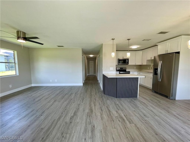 kitchen featuring appliances with stainless steel finishes, sink, light hardwood / wood-style flooring, white cabinets, and hanging light fixtures