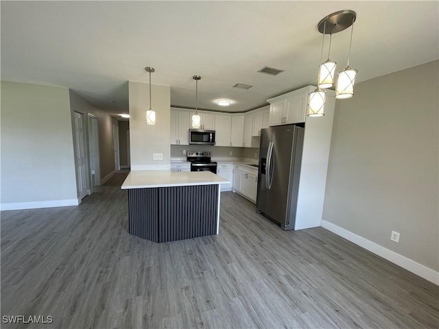 kitchen featuring decorative light fixtures, light wood-type flooring, stainless steel appliances, and white cabinetry