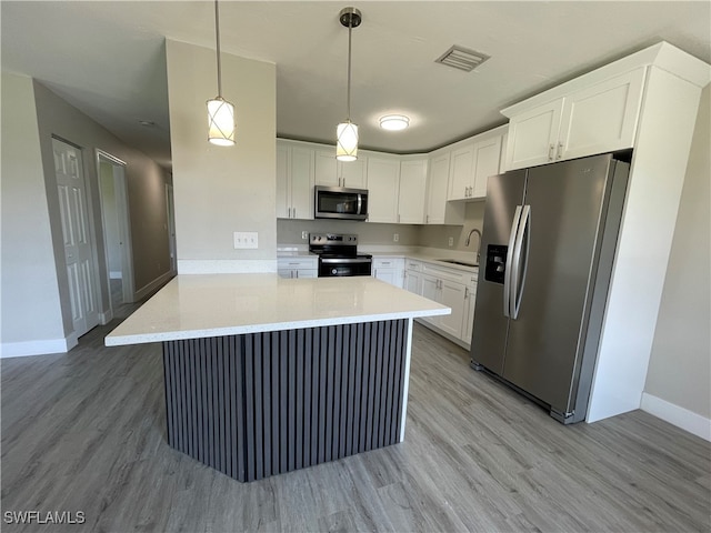 kitchen with stainless steel appliances, hanging light fixtures, and white cabinets