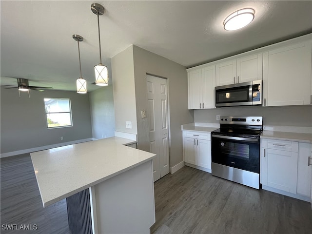 kitchen featuring kitchen peninsula, white cabinetry, decorative light fixtures, and appliances with stainless steel finishes