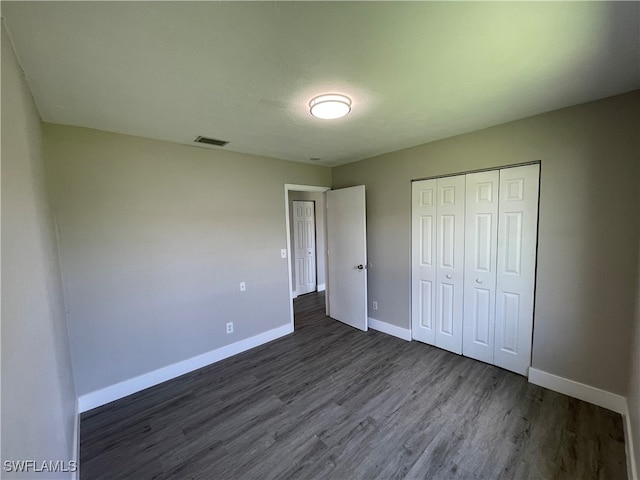 unfurnished bedroom with dark hardwood / wood-style flooring and a closet