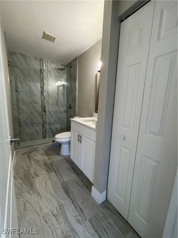 bathroom featuring a shower with door, vanity, and toilet