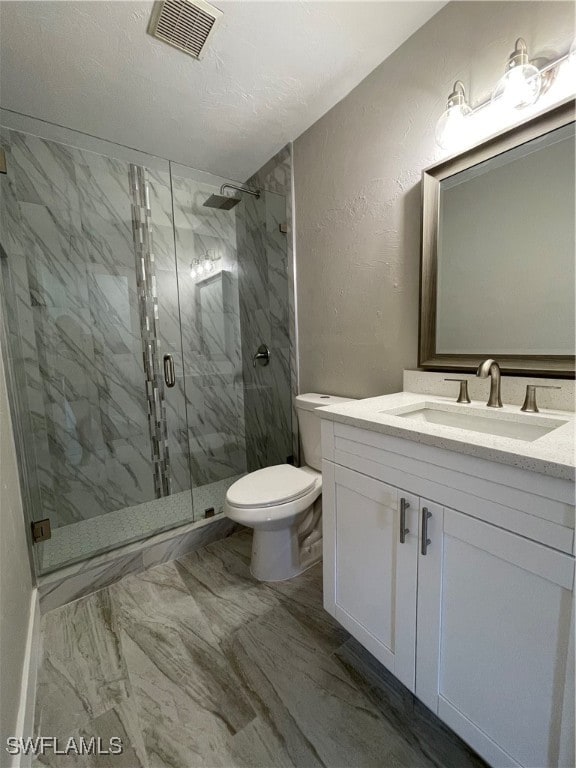 bathroom with vanity, a shower with shower door, and toilet