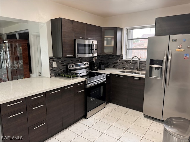 kitchen featuring sink, backsplash, appliances with stainless steel finishes, and dark brown cabinetry