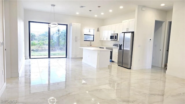 kitchen featuring white cabinetry, appliances with stainless steel finishes, a center island, pendant lighting, and sink