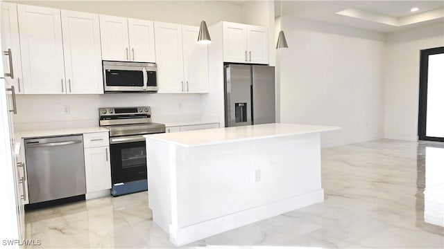 kitchen featuring a center island, a raised ceiling, white cabinetry, hanging light fixtures, and stainless steel appliances