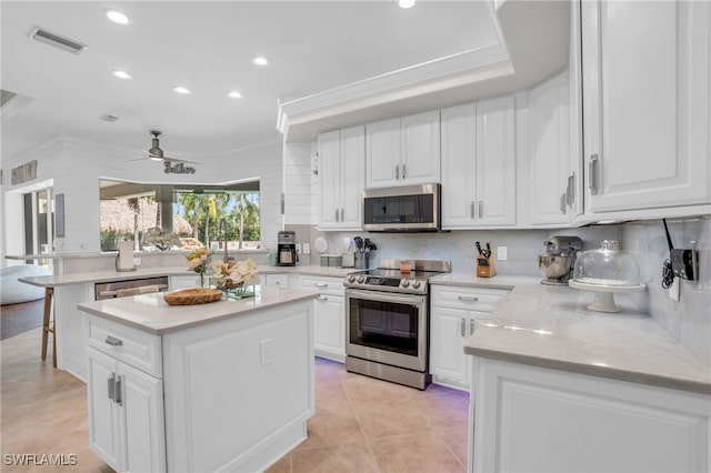 kitchen with ceiling fan, white cabinetry, appliances with stainless steel finishes, and a center island