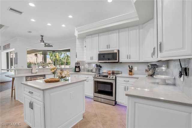 kitchen with a center island, visible vents, appliances with stainless steel finishes, white cabinets, and light stone countertops