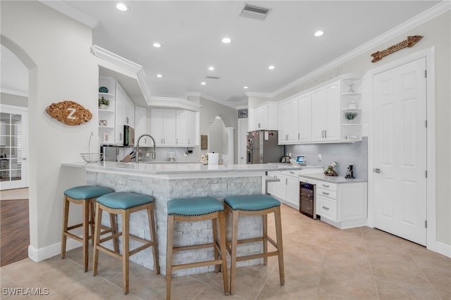 kitchen featuring light hardwood / wood-style floors, crown molding, stainless steel fridge, kitchen peninsula, and white cabinets