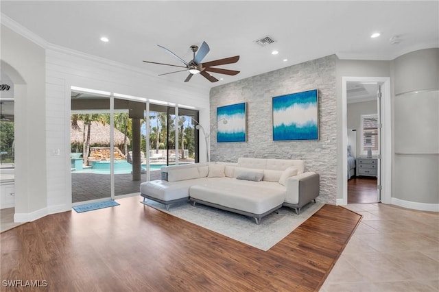 living room with baseboards, ornamental molding, visible vents, and recessed lighting