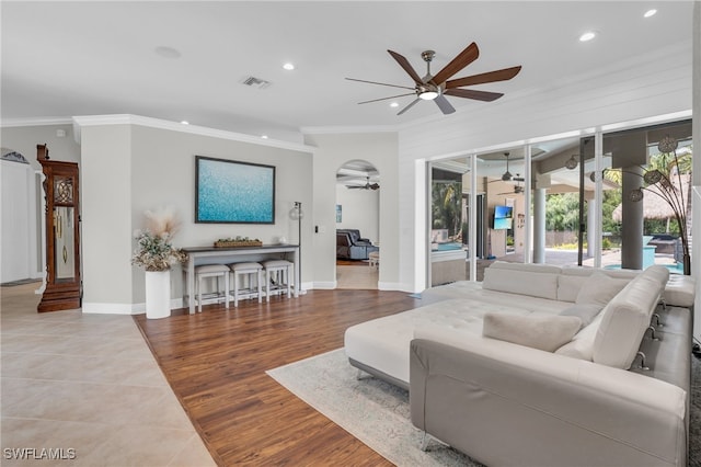 living room featuring ceiling fan, light tile patterned flooring, ornamental molding, and a healthy amount of sunlight