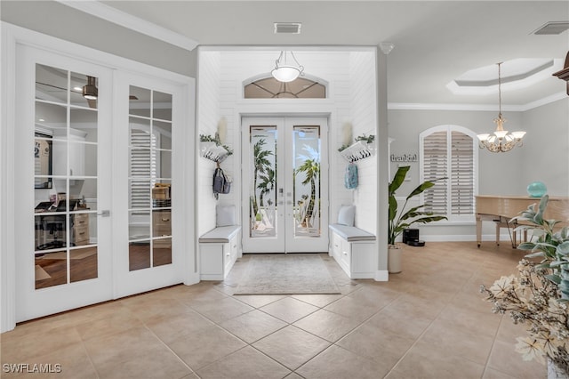 tiled entryway with crown molding, an inviting chandelier, and french doors