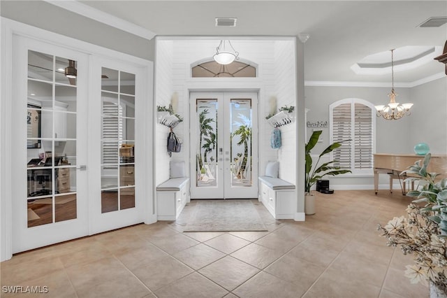 entrance foyer with visible vents, ornamental molding, a chandelier, and french doors