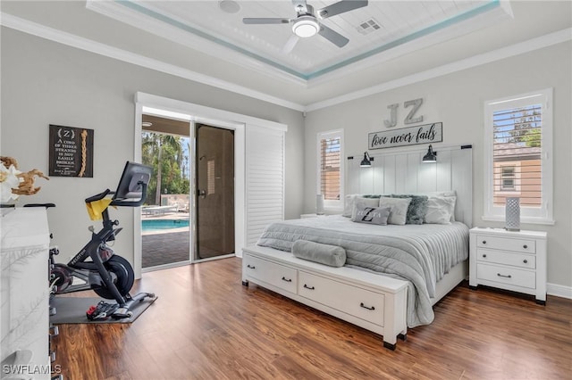 bedroom featuring access to outside, a raised ceiling, visible vents, and multiple windows