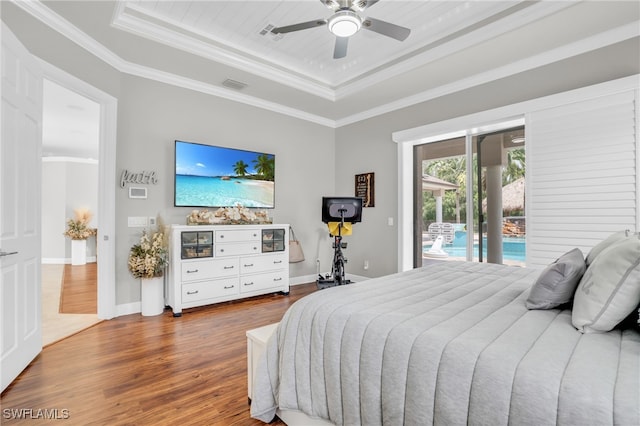 bedroom with ceiling fan, a tray ceiling, hardwood / wood-style floors, ornamental molding, and access to exterior