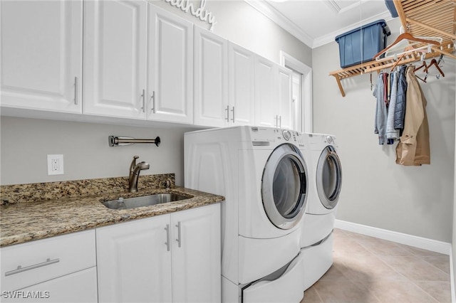 laundry room featuring washing machine and clothes dryer, cabinet space, ornamental molding, a sink, and baseboards