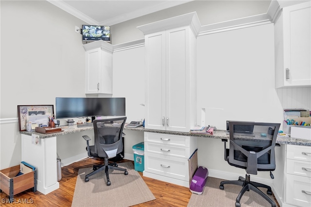 office area featuring light wood-type flooring, crown molding, and built in desk