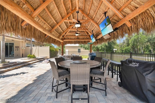 view of patio with grilling area, a gazebo, outdoor dining space, ceiling fan, and fence