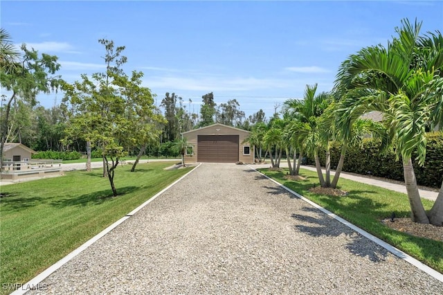 surrounding community with gravel driveway, a detached garage, and a yard