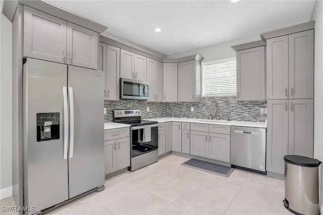 kitchen with decorative backsplash, appliances with stainless steel finishes, light countertops, and a sink