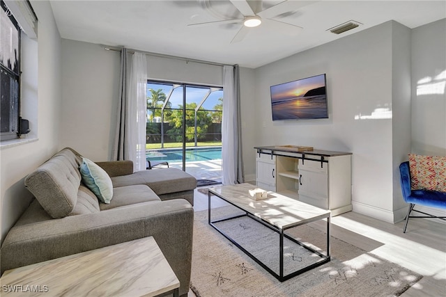 living area with ceiling fan, wood finished floors, a sunroom, visible vents, and baseboards