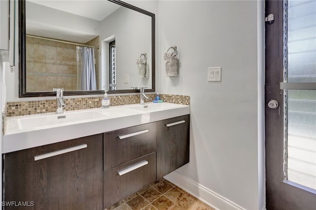 full bathroom featuring double vanity, baseboards, backsplash, and a sink