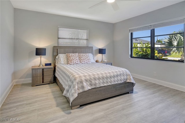 bedroom with a ceiling fan, light wood-style flooring, and baseboards