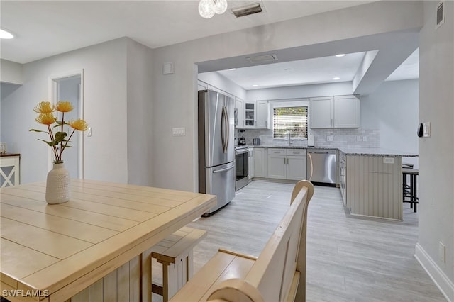 kitchen with a breakfast bar, stainless steel appliances, tasteful backsplash, visible vents, and a peninsula