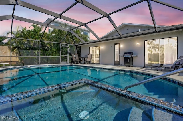 view of swimming pool featuring a pool with connected hot tub, a patio area, area for grilling, and a lanai