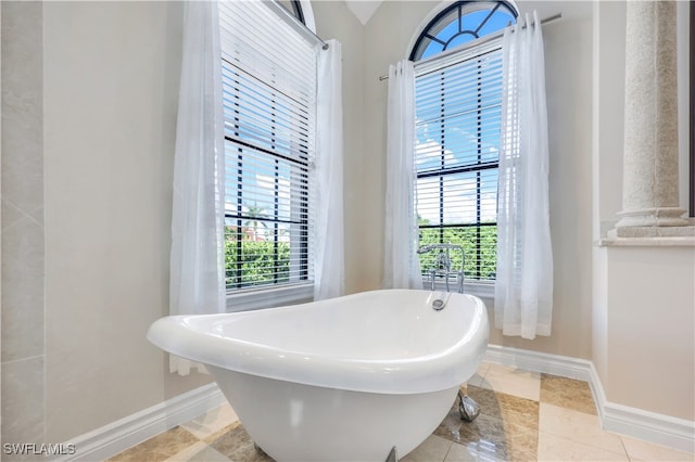 bathroom featuring tile patterned floors, a bath, and a healthy amount of sunlight