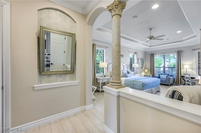 bedroom with light hardwood / wood-style flooring, ceiling fan, a raised ceiling, ornamental molding, and decorative columns